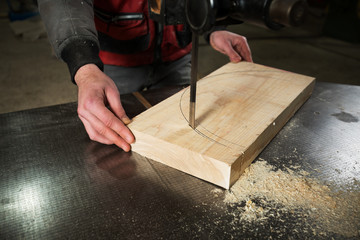 A carpenter cuts a piece of wood to the machine