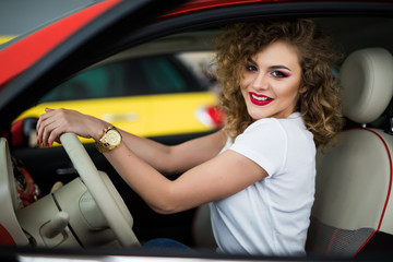 Fototapeta na wymiar Pretty young woman driving her new car and look at camera from window