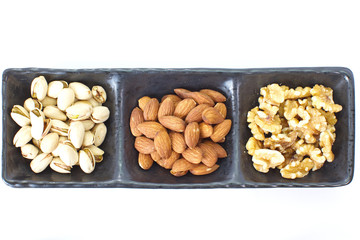 Assorted mixed nuts in black plate on white background