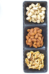Assorted mixed nuts in black plate on white background