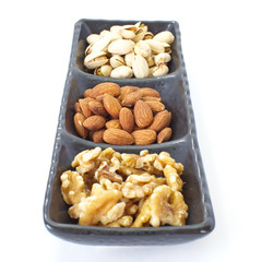Assorted mixed nuts in black plate on white background