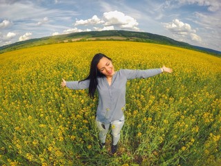 Fototapeta premium Emotional portrait of young beautiful woman in rapeseed field
