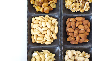 Assorted mixed nuts in black plate on white background