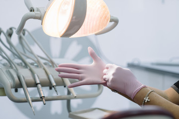 Close up of female doctor's hands putting on blue sterilized surgical gloves in the office. - Powered by Adobe