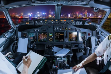 Papier Peint photo autocollant Hong Kong Airplane cockpit flying on Hong Kong panorama skyline with pilots arms and blank white papers for copy space.