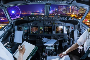 Fototapeten Airplane cockpit flying on cityscape of Hong Kong, Central District, with Observation Ferris Wheel at Victoria Harbour illuminated at night. © bennymarty