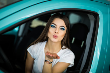 Fototapeta na wymiar Young girl was driving the car. Woman sends an air kiss.