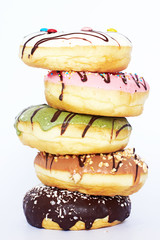 Tower of assorted donuts with different flavors (strawberry, pistachio, vanilla, caramel, chocolate) isolated. Close-up, white background. 