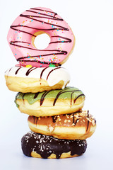 Isolated pile of assorted donuts (chocolate, pistachio, caramel, vanilla, strawberry flavor) on...