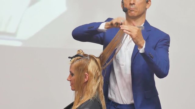 Hairdresser In Action. Barber and customers. hairstyle models for white hair. Blonde in the cabin. Work in the cabin. Barber shears white hair model client. close-up.