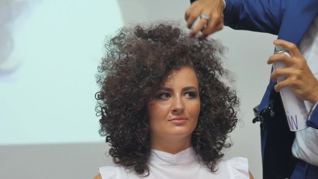 Hairdresser In Action. Barber makes a hair dryer dries hair curly brunette. Blonde in the cabin. Barber makes a hair dryer dries hair curly brunette in beauty salon