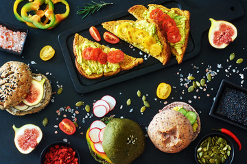 Top view of variety of vegetarian sandwiches and burgers with avocado, radish, cream cheese, figs, pumpkin seeds, pepper and tomato. Healthy snack concept. 