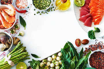 High protein dinner ingredients food frame. Salmon and tuna sashimi, cooked shrimps, clamps, brown rice, asparagus, spinach, olive oil, salt and pepper. White background, copy space.