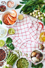 High protein meal ingredients. Vertical top view of cooked shrimps, clamps, raw peas and brown rice, spinach, baby eggplant, asparagus, lime, salt and pepper and vichy towel. Copy space.