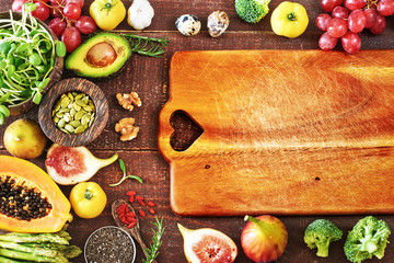 Top view of fresh fruits and veggies and rustic wooden board with empty space. Vegetarian or clean-eating concept. 