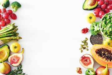 Fresh veggies and fruits frame on white background with copy space. Detox or clean-eating concept with avocado, papaya, grape, broccoli, figs, nuts, seeds, superfoods. 