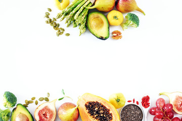 Fresh veggies and fruits frame on white background with copy space. Detox or clean-eating concept with avocado, papaya, grape, broccoli, figs, nuts, seeds, superfoods. 