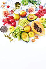 Clean eating or raw diet food vertical background with a copy space. Top view of fresh vegetables, fruits, seeds and nuts (papaya, asparagus, figs, broccoli, avocado, grape, tomato, goji, chia).