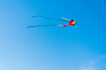 Naklejka na ściany i meble Beutiful colorful kite flying in the wind with blue sky in background.