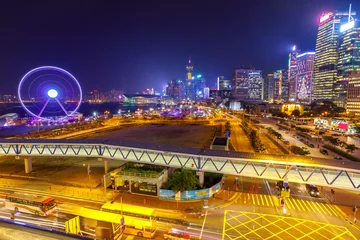 Fotobehang Spectacular aerial view of cityscape in Hong Kong, Central District, with Observation Ferris Wheel at Victoria Harbour illuminated at night. © bennymarty