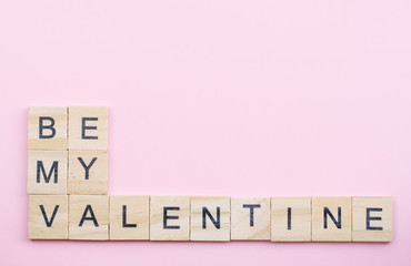 Text wooden blocks spelling the word be my  valentine on pink background