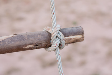 A rope is tied in a knot around a fence post , rope tied knot wood pole