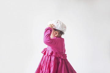 child walking in a pink dress with hat on