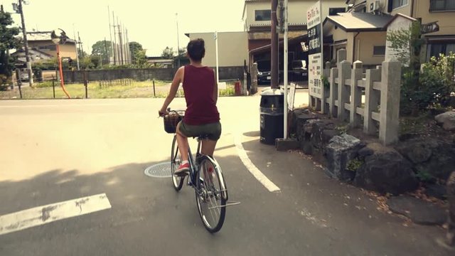 Young woman biking in Kyoto country taking a right turn and entering the wrong lane