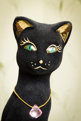 A statuette of a black cat with a jewel on the neck.