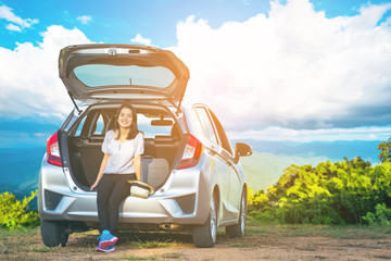 Obraz premium Woman traveler sitting on hatchback car with mountain background in vintage tone