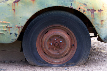 Close up.close up of a flat tire of a rusty old car on dirt road. Rusted wheel of old car.