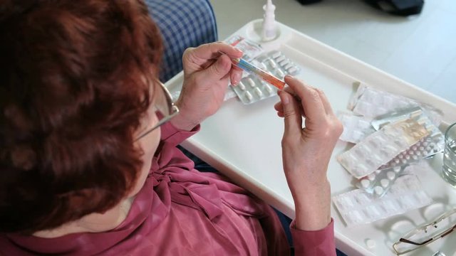 Old woman with fever checking mercury thermometer