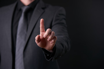 Businessman in trendy black suit using virtual touchscreen isolated on black background.Touch screen business futuristic concept, finger push interface, design template.