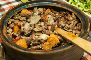 Clay pot with boiled and baked beans with onions, carrots and spices