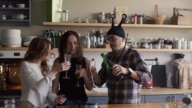 man is opening bottle of champagne on a home kitchen party