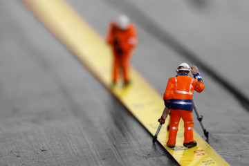 Scale model construction workers on a tape measure with selective colour