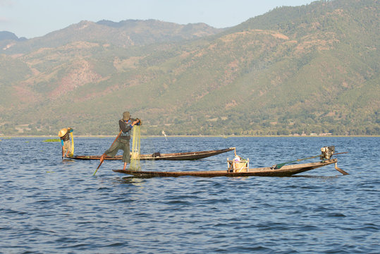 Two fishermen in traditional wooden boats to catch fish on the Inle lake. Myanmar