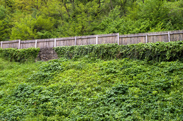 Wooden fence on a green hill.