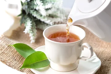Photo sur Plexiglas Theé Gros plan versant du thé noir chaud dans une tasse de thé blanc, concept de l& 39 heure de la cérémonie du thé