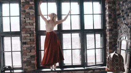 Ballet dancer in a bright red skirt on the background of the window