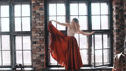 Ballet dancer in a bright red skirt on the background of the window