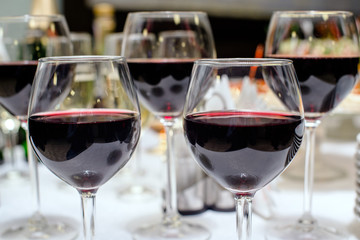 Several glasses with red wine stand on the banquet table