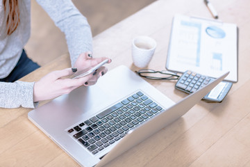 Young woman in office typing on smart phone, people from generation Z