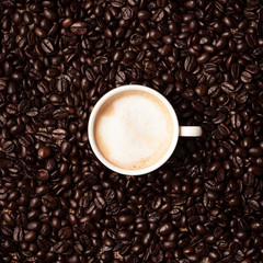 Coffee cup top view on roasted coffee beans background
