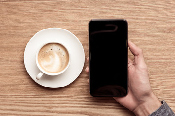 Fototapeta na wymiar Hands using mobile phone and digital tablet with coffee mug top view shot.