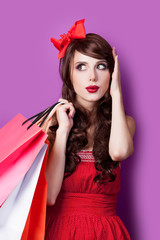 photo of beautiful young woman with shopping bags in santa claus hat on the wonderful purple background