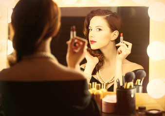 Fototapeta na wymiar photo of beautiful young woman holding her lipstick near the window with lights