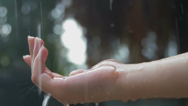 Women's hand covered in droplets of heavy rain in close-up