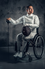Fototapeta na wymiar Female fencer in wheelchair holds safety mask and a sword.