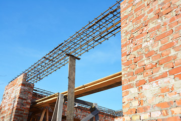 Unfinished Red Brick House Wall Under Construction without Roofing. Lintel Construction. Rebar steel bars on home construction, reinforcement bars with wire rod as a lintel for window.